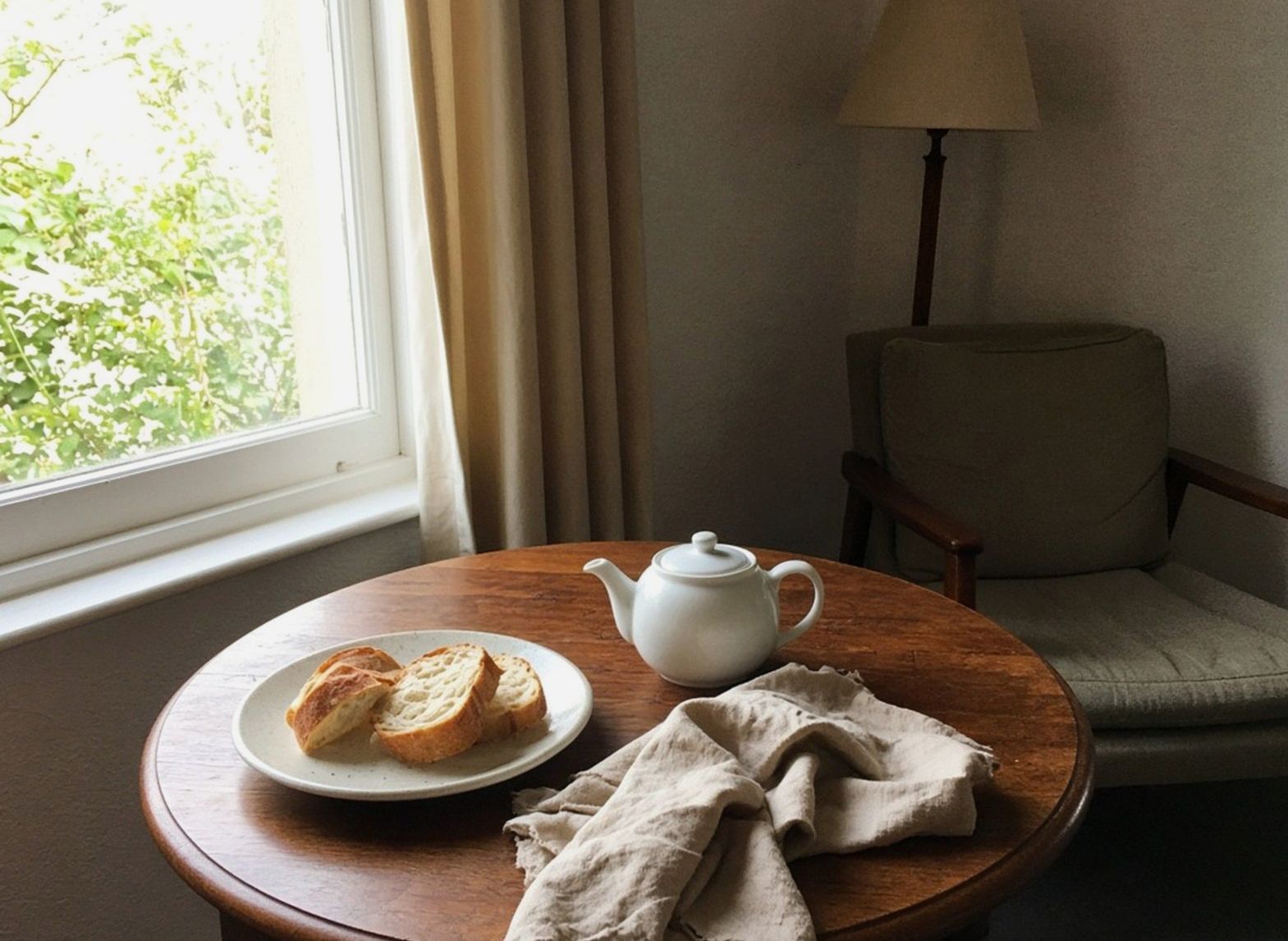 Breakfast table with a teapot, bread and a crumpled napkin