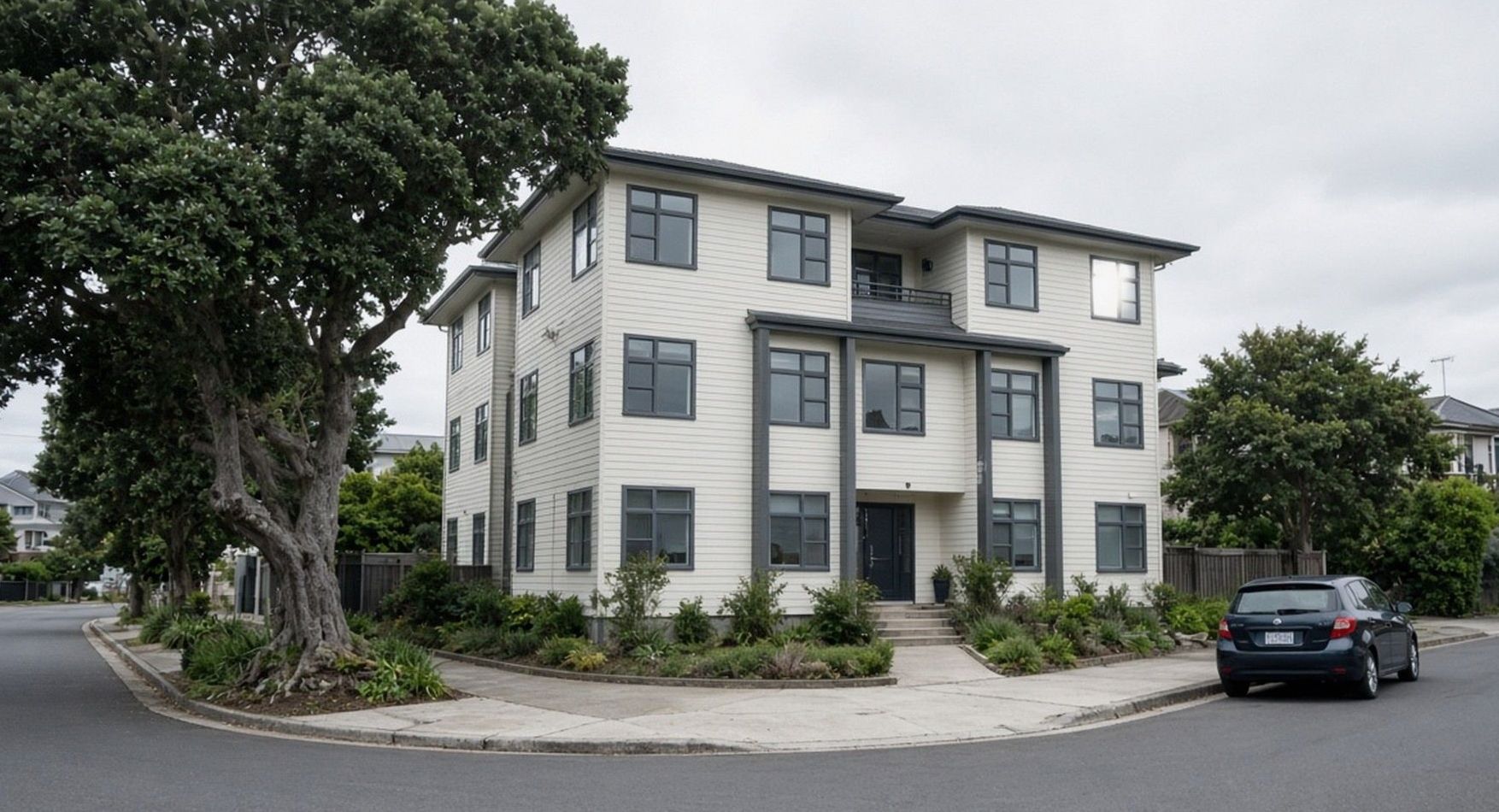 Three-storey cream hotel with a pohutukawa at the kerb on Cobham Crescent